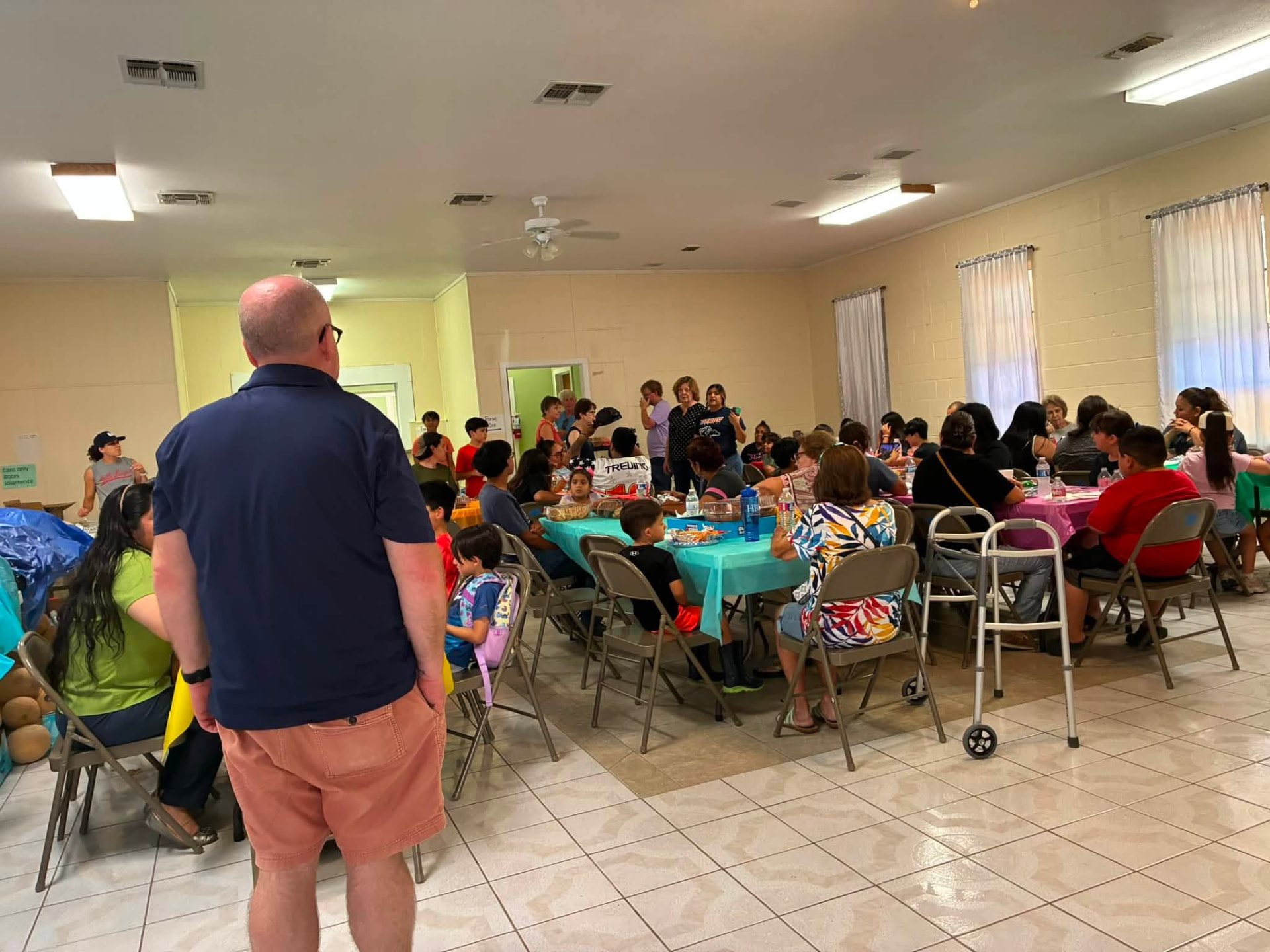 Families sharing a meal and activities inside a Rio Grande Valley church fellowship hall